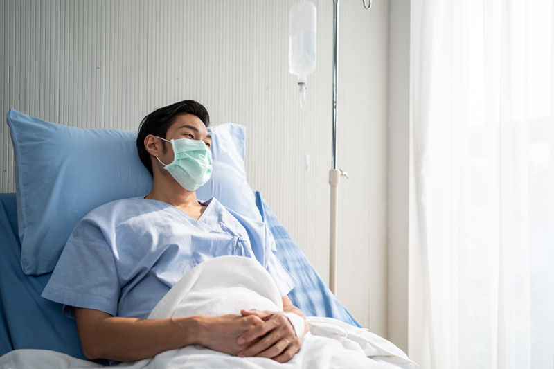 asian male patient lying on bed with face mask